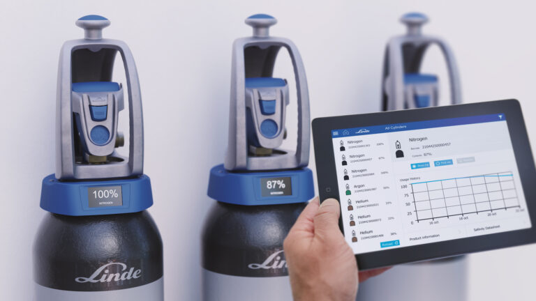 Man holding a tablet showing the interface in front of the Linde gas bottles